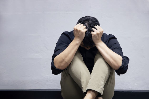 Foto o empresário de depressão sentado perto da parede no chão