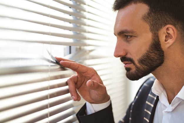 O empresário olhando pelas cortinas