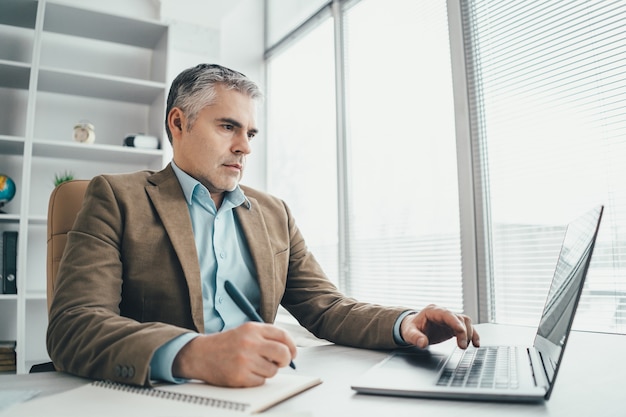 O empresário trabalhando com um laptop na mesa