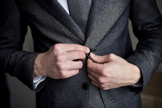 O empresário usa uma jaqueta, closeup de mãos masculinas, noivo se preparando de manhã antes da cerimônia de casamento