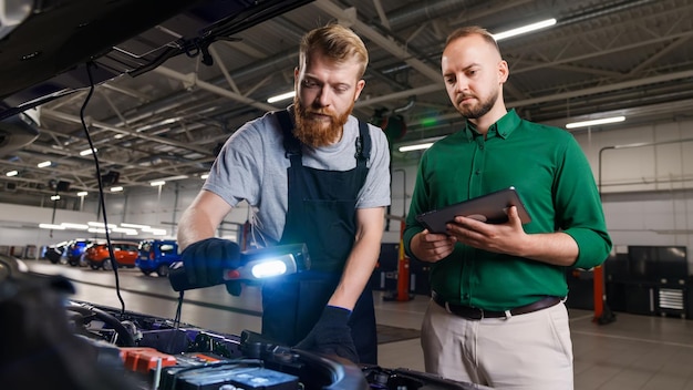 O engenheiro automotivo verifica todos os componentes e peças sob o capô do carro e o gerente faz um relatório no tablet