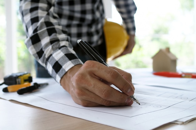 O engenheiro-chefe entrega a caneta para verificar a planta do edifício