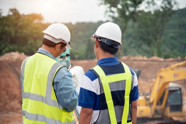 O engenheiro de pesquisa no canteiro de obras usa o teodolito que verifica trabalho de fundação de escavação