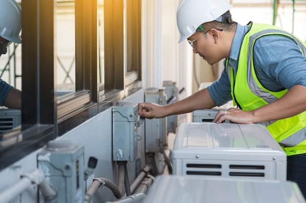 O engenheiro eletricista está verificando e fazendo a manutenção do sistema de ar condicionado.