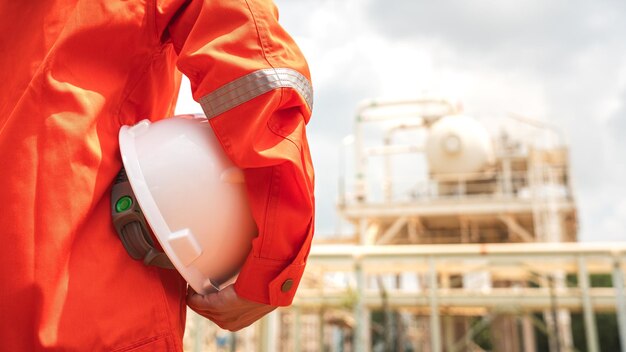 Foto o engenheiro está segurando um capacete de segurança branco com fundo de fábrica de produtos químicos segurança de trabalho