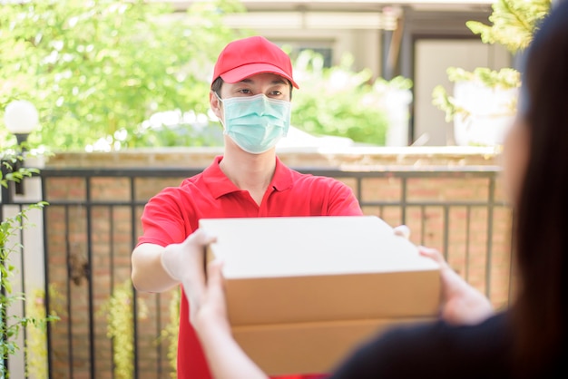 O entregador de máscara e luvas protetoras entrega comida de caixa durante o surto de vírus. entrega em domicílio segura.
