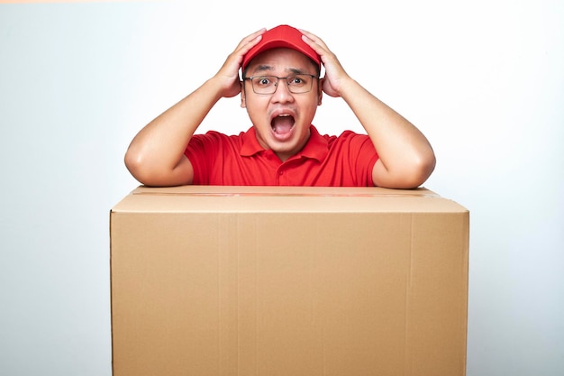 O entregador nervoso de uniforme vermelho tem muito trabalho, pois os clientes fazem pedidos em lojas on-line apoiados em caixas de papelão