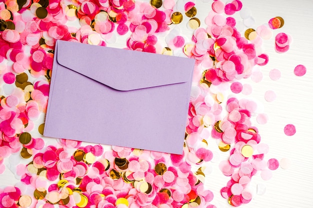 O envelope roxo repousa sobre um fundo de confetes multicoloridos, um design festivo