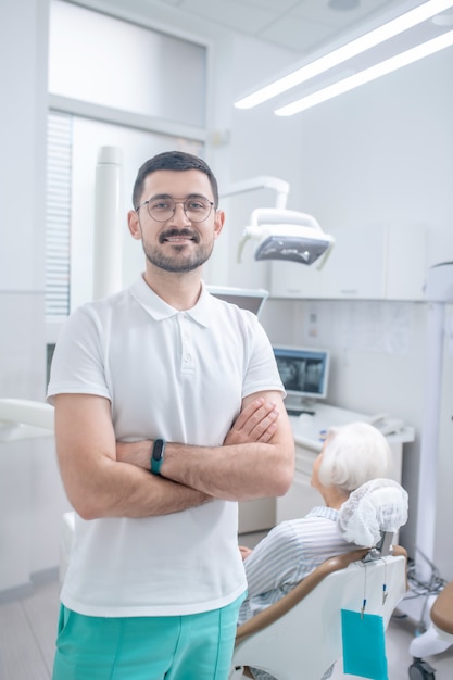 O escritório de dentista. Jovem dentista do sexo masculino tendo uma consulta com uma paciente sênior do sexo feminino