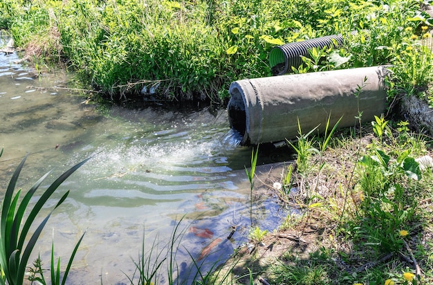 O esgoto flui pelo cano de drenagem de esgoto para o rio Poluição ambiental