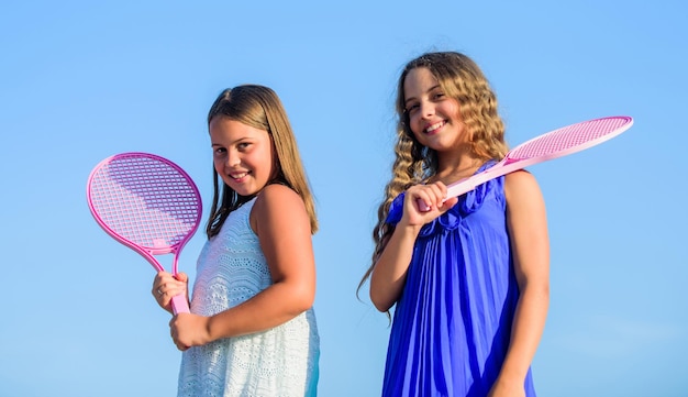 O esporte é a nossa vida meninas pequenas com raquete de tênis atividade esportiva de verão crianças energéticas feliz e alegre jogo esportivo jogando jogos de verão jogar tênis infância felicidade e irmandade
