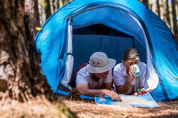 O estilo de vida de um casal de aposentados aproveita viagens, turismo, férias, deitado dentro de uma barraca em acampamento selvagem gratuito ao ar livre - pessoas idosas e se sentindo com a natureza floresta experiência na floresta - viajante idoso