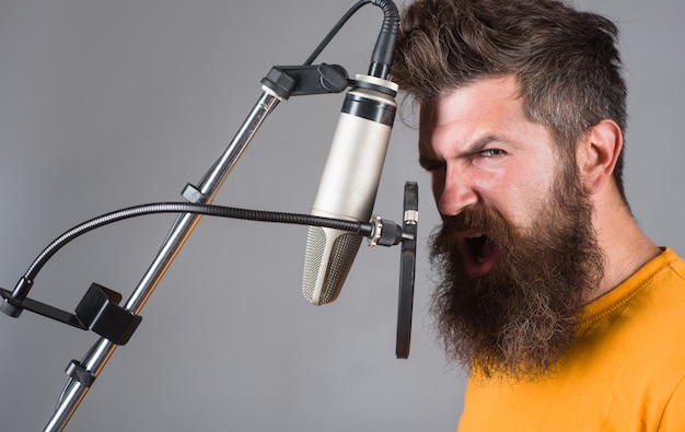 O estúdio grava um homem barbudo cantando no microfone karaokê cantando com um microfone cantando