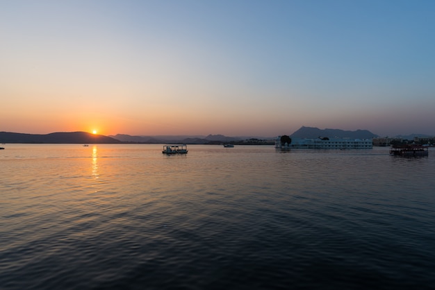 O famoso palácio branco no lago Pichola ao pôr do sol.