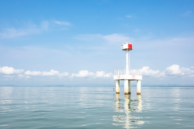 O farol no mar com efeito da água nuvem e céu do fundo.