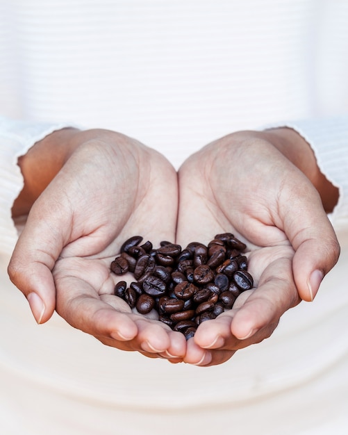 O feijão de café do close up nas mulheres entrega o conceito para a profundidade de campo rasa do bom dia.