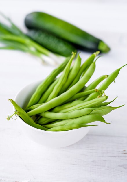 O feijão verde na chapa branca com vegetais verdes