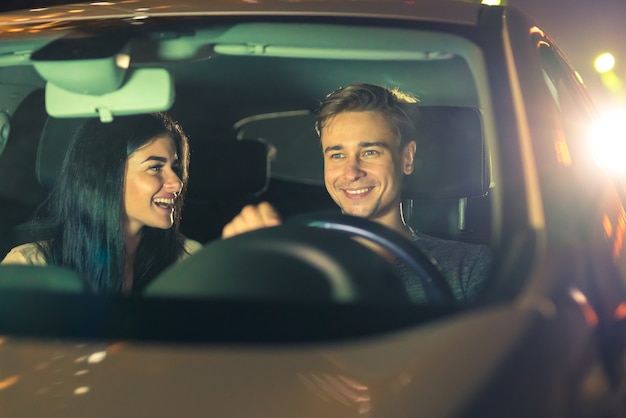 O feliz casal dirige um carro. noite noite
