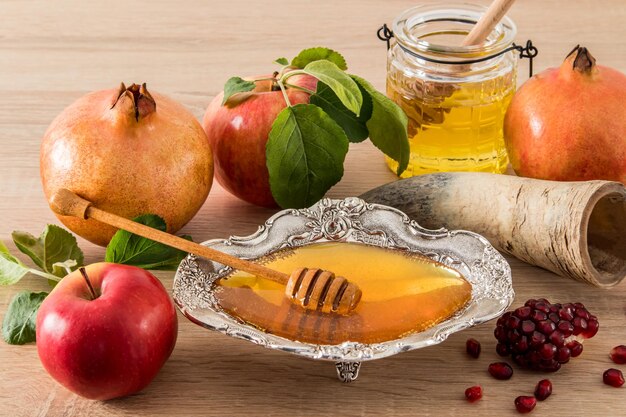 O feriado religioso judaico de Roshashana, uma composição de guloseimas tradicionais, mel em uma tigela de prata, maçãs, romã e seus grãos