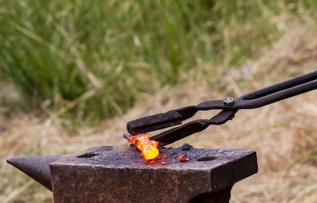 O ferreiro põe o ferro quente em uma bigorna para forjar
