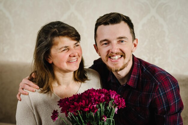 O filho dá flores para a mãe e parabenizou o dia das mães Retrato pai abraçando a avó sorrindo e passando tempo juntos em casa Dia Internacional da Mulher Feliz conceito de férias