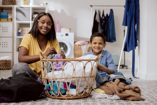 O filho do retrato ajuda a mãe nas tarefas domésticas as mulheres classificam as roupas dobradas