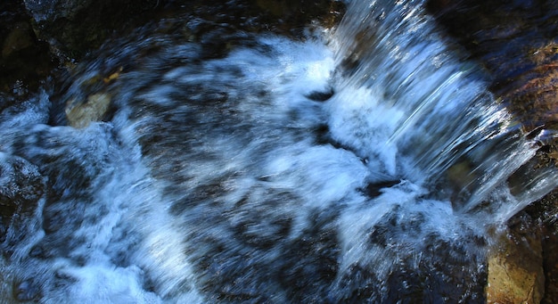 O fluxo de água em uma pequena cachoeira na vista superior do riacho da montanha