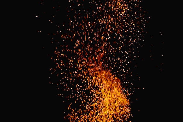 Foto o fogo da fogueira arde com faíscas em um fundo escuro