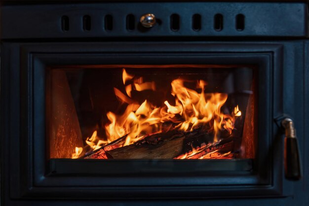 Foto o fogo queimado em uma lareira de fogão de madeira irradia calor para o interior da casa
