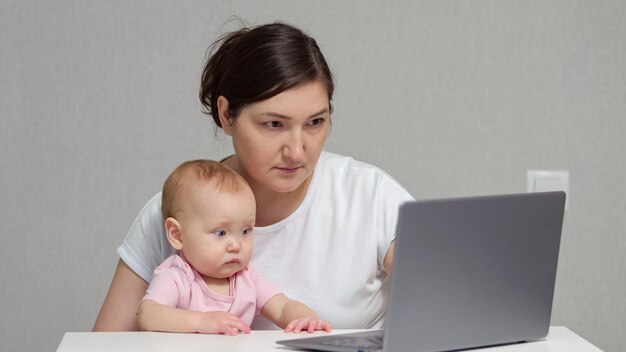 O freelancer de cabelos castanhos trabalha no laptop com a filha bebê