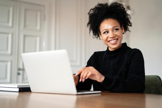 O freelancer trabalha remotamente em um laptop Uma designer feminina satisfeita sorri para um