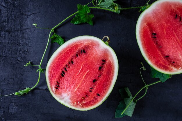 O fruto da melancia fresca cortou ao meio em um fundo preto.