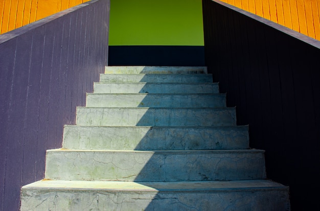 Foto o fundo da luz solar e a sombra nas etapas de pedra brancas surgem da escadaria colorida na opinião de baixo ângulo e de perspectiva, imagem para o conceito de projeto exterior da decoração da casa.