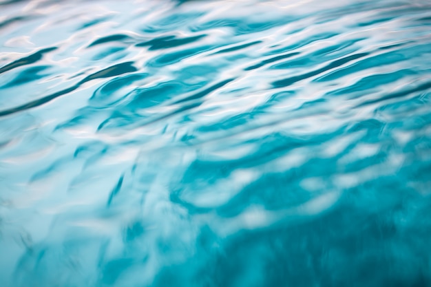 O fundo de água azul natural suave com bokeh abstrato no mar