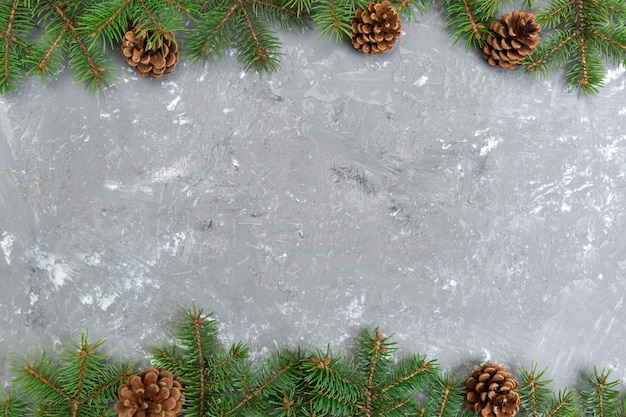 O fundo de madeira do cimento cinzento do Natal com quadro e cones da árvore de abeto copia o espaço. vista superior, espaço vazio