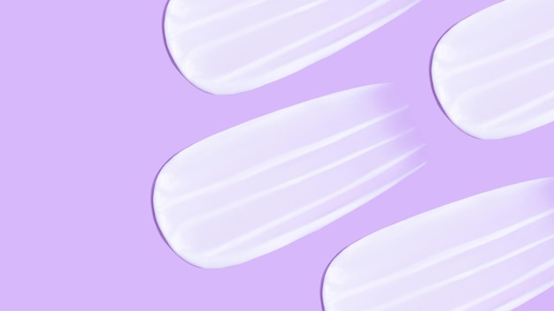 O fundo é cosmético Muitas manchas de creme em um fundo roxo rosa