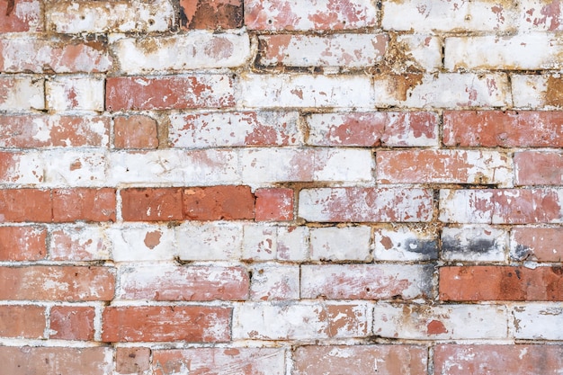 O fundo sólido e rústico da parede de tijolos parece destruído e tem pintura velha descascada. Camada plana para mock up e modelo ou cartão com espaço de texto.