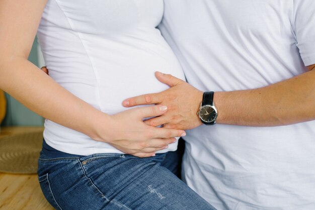 O futuro pai segura a mão na barriga da futura mãe, sua esposa grávida. pais expectantes esperando seu bebê