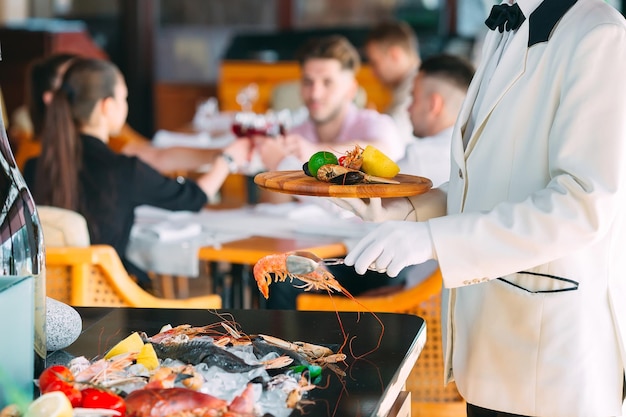 O garçom coloca os frutos do mar em uma bandeja no restaurante.