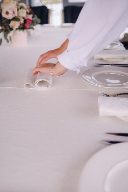 O garçom coloca um guardanapo branco no prato Linda mesa para férias sem comida