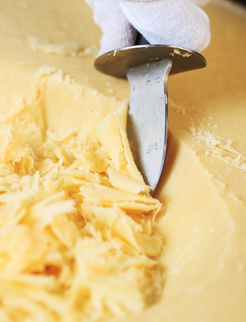 O garçom corta pedaços de queijo parmesão