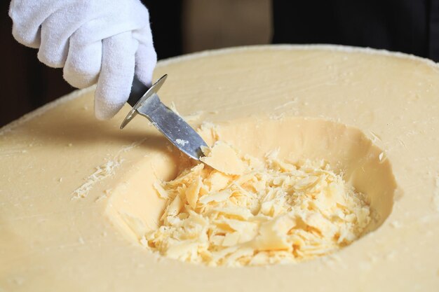 O garçom corta pedaços de queijo parmesão