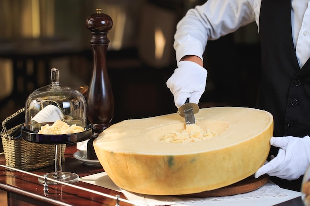 Foto o garçom corta pedaços de queijo parmesão