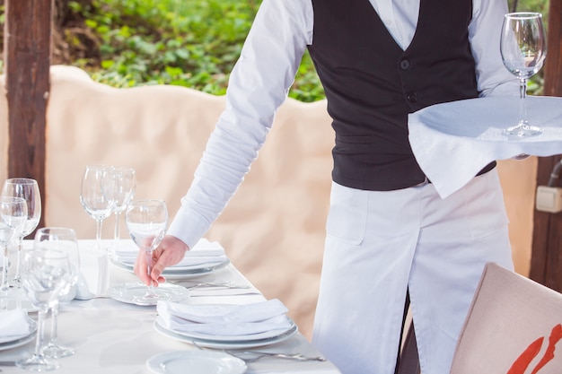 O garçom trabalha em um restaurante no terraço de verão