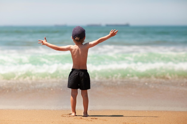 O garoto está acenando com as mãos comandando o mar