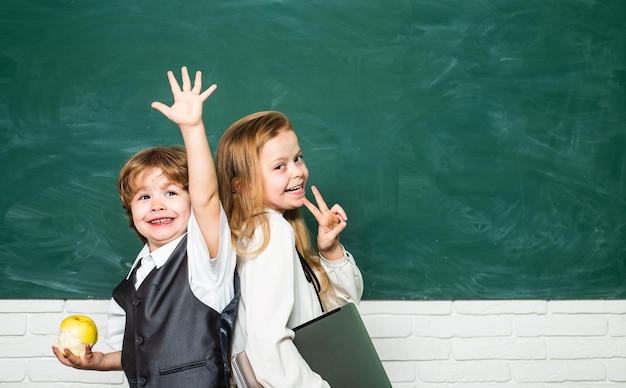 O garoto está aprendendo na aula sobre o fundo do quadro-negro casal de colegial e colegial da primeira série