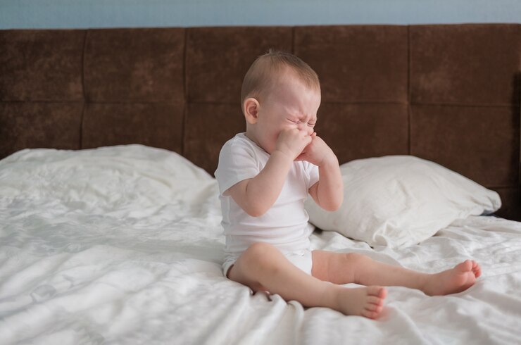 Foto o garoto está chateado. o bebê senta na cama e chora