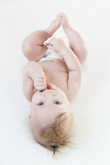 Foto o garoto loiro de cinco meses de olhos azuis está mentindo, sorrindo fofo