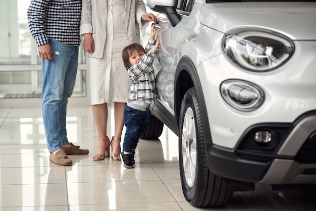 O gerente ajuda a jovem família a escolher o carro mais confortável para a cidade.