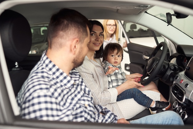 O gerente ajuda a jovem família a escolher o carro mais confortável para a cidade.